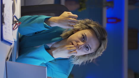 Vertical-video-of-Home-office-worker-woman-biting-her-nails-looking-at-camera.